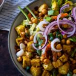 Eine mit veganem Cobb-Salat gefüllte Schüssel auf einem Tisch mit einem Stuhl im Hintergrund