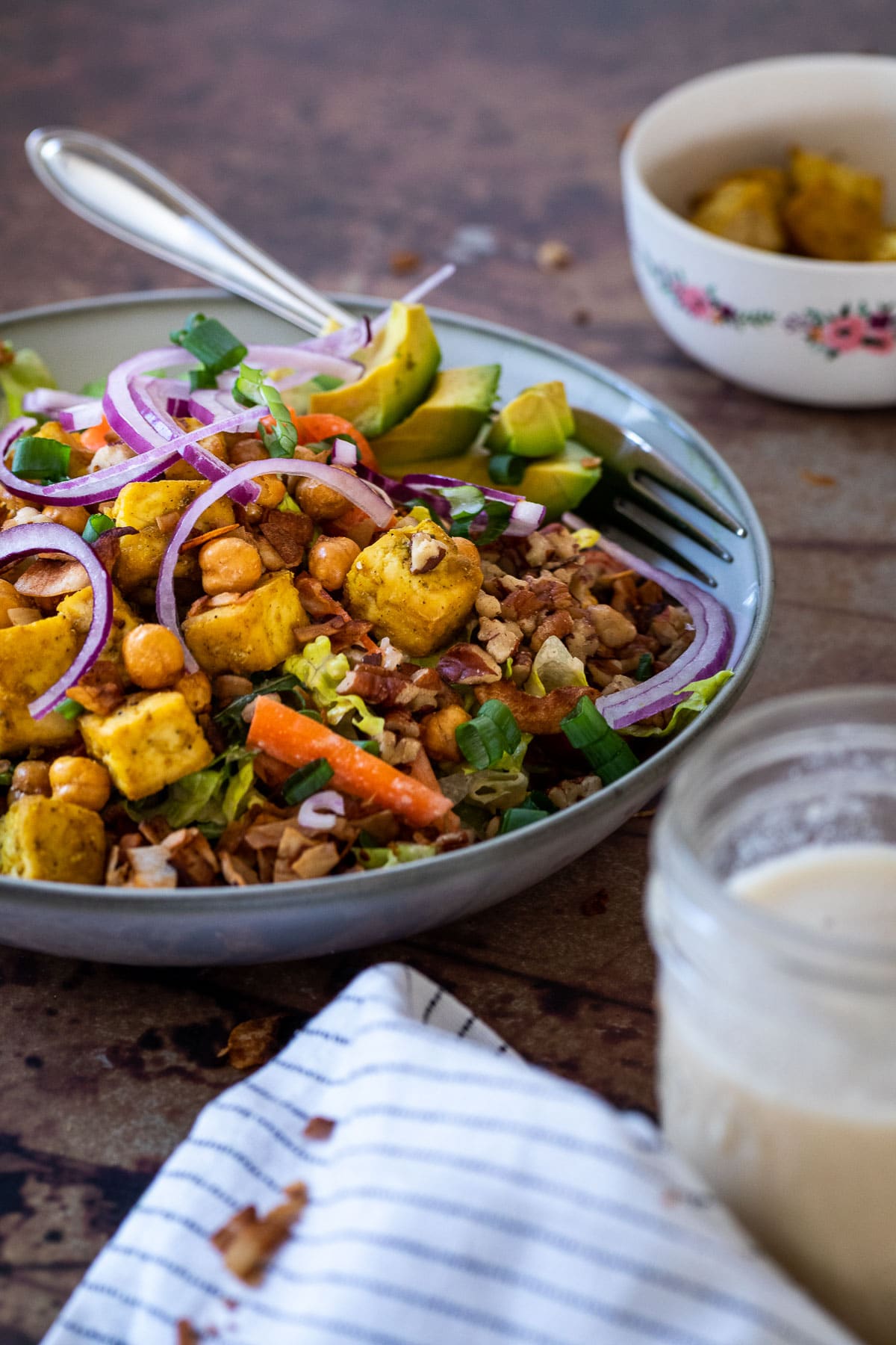 Eine mit veganem Cobb-Salat gefüllte Schüssel auf einem Tisch mit einem Stuhl im Hintergrund