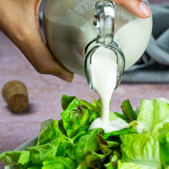 Vegane Knoblauch Joghurt Soße wird über Salat geschüttet