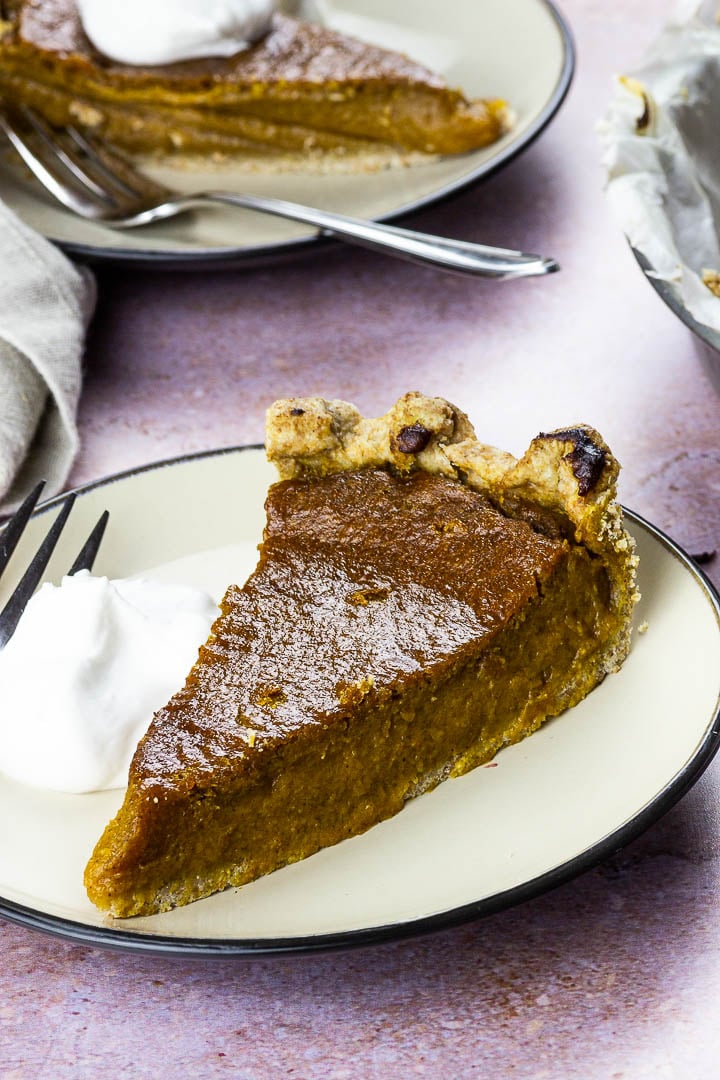 Veganer Kürbiskuchen auf einem Teller mit Kokossahne für dein nächsten Nachtisch