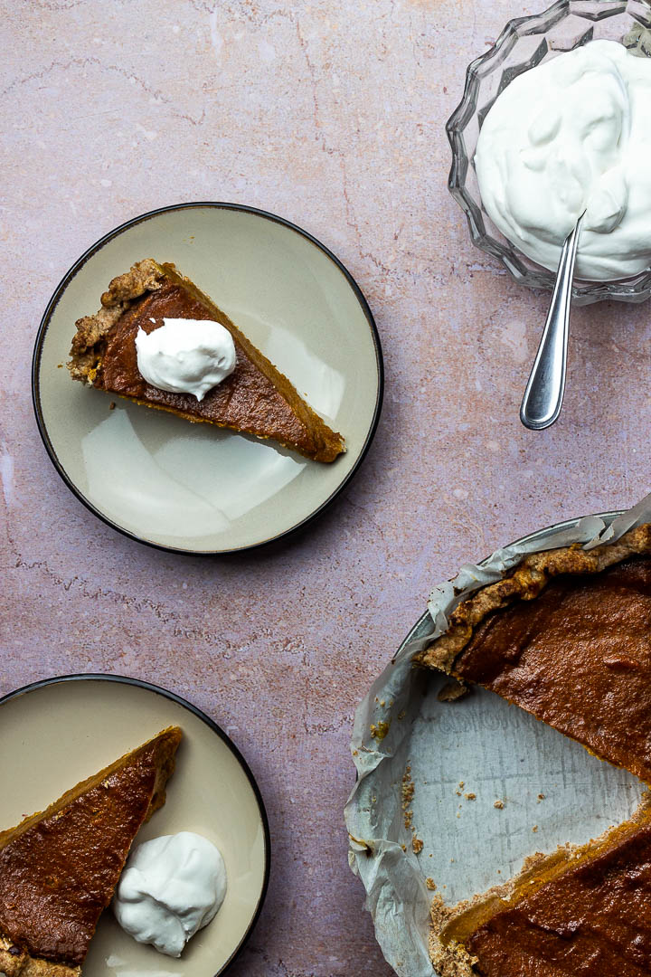 Veganer Kürbiskuchen auf einem Teller mit Kokossahne für dein nächsten Nachtisch