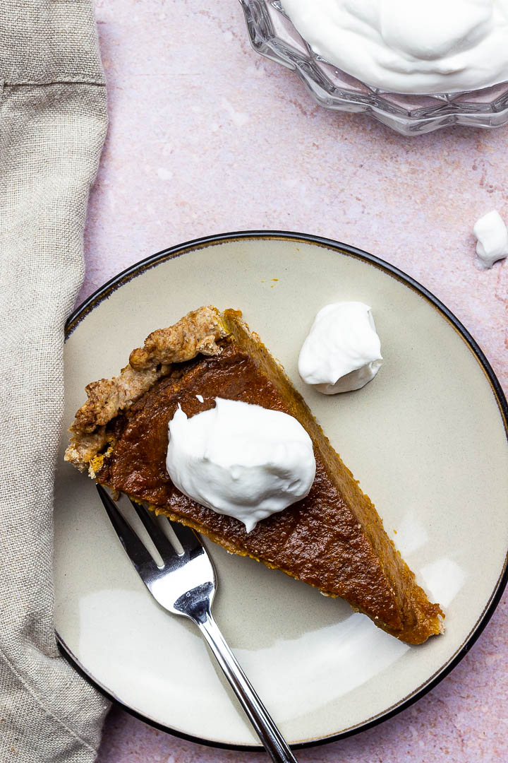 Vegan Pumpkin Pie Slice on a Plate with Whipped Coconut Cream for a Thanksgiving Dessert