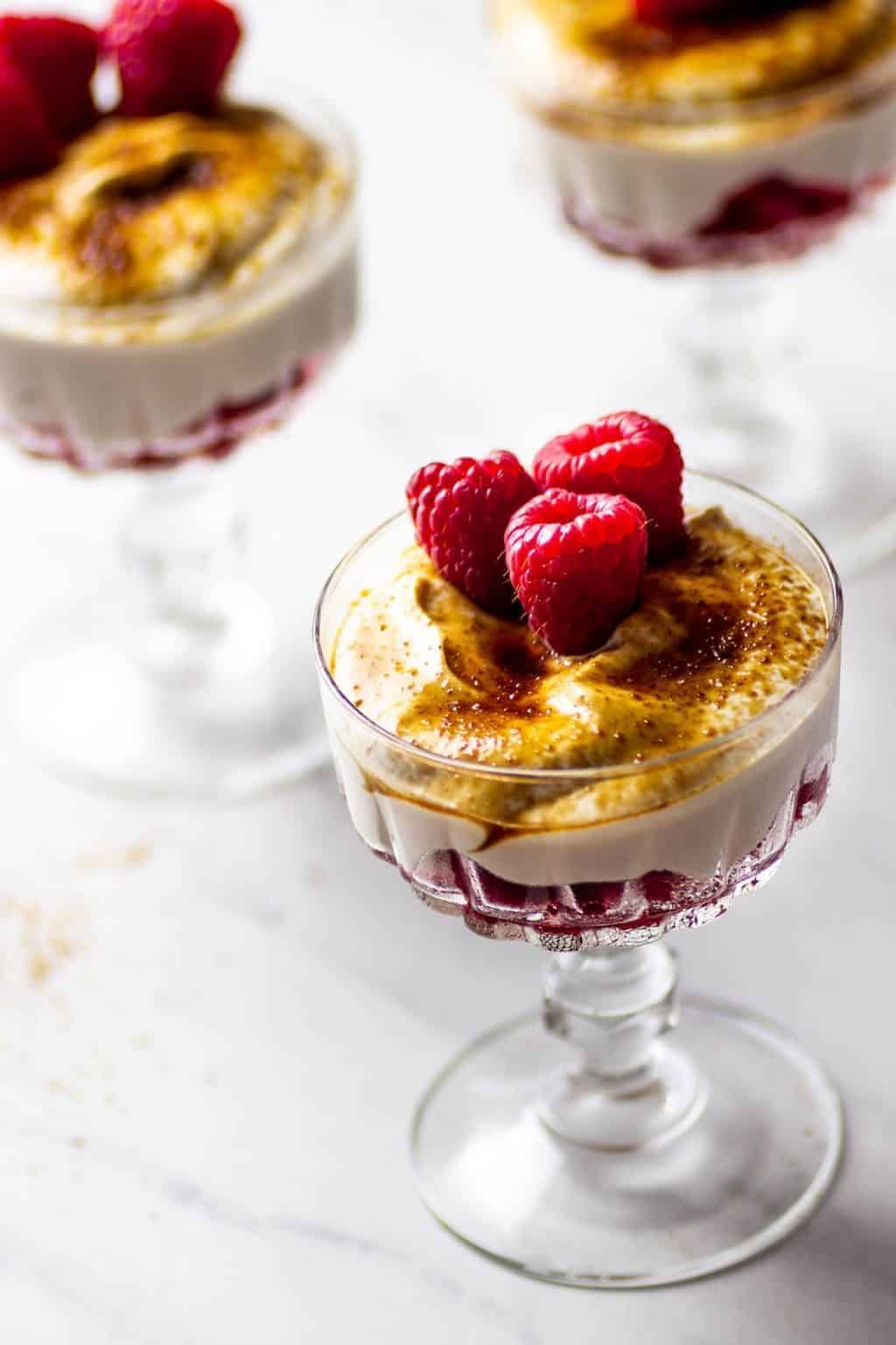 Veganer Nachtisch mit Himbeeren und einer laktosenfreien Creme, getopped mit Kokosblütenzucker oder Rohrohrzucker