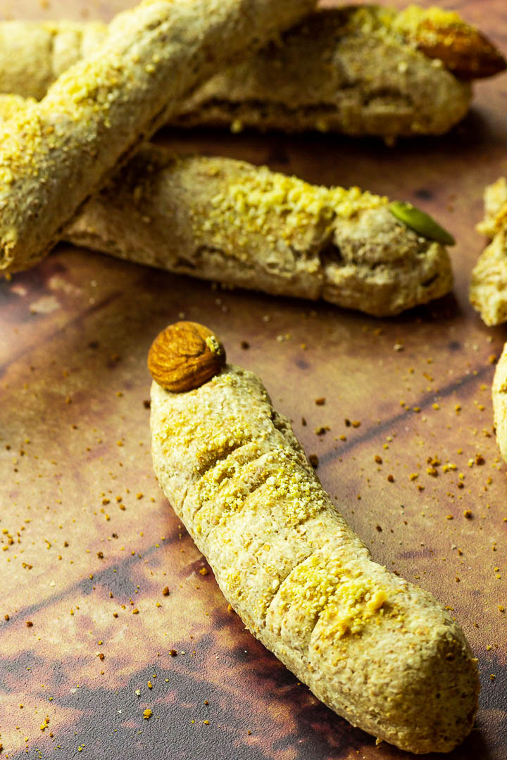 Halloween Brotstangen in Form von Hexenfinger mit veganem Parmesan Käse und Mandel / Kürbiskerne Fingernägel. Knusprig und luftige Brotstangen zubereitet aus Dinkelvollkorn Pizzateig.