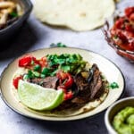 Vegane Blech Fajitas mit Portobello Pilze, Paprika, Zwiebeln serviert in einer gusseisernen Pfanne mit Tortillas, Salsa und Guacamole
