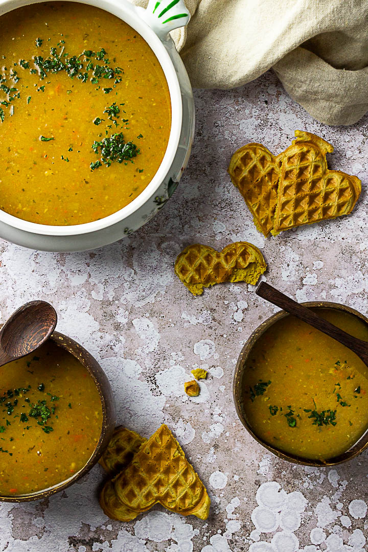 Kartoffelsuppe in Schüsseln serviert daneben liegen Herzwaffeln