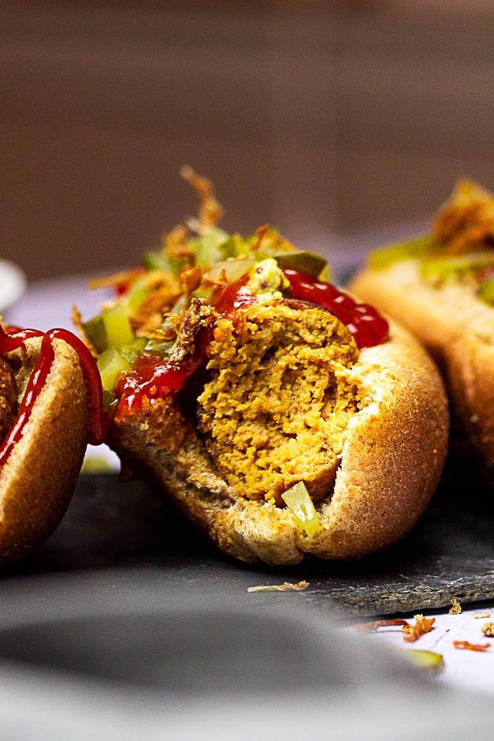 Vegan Hot Dogs made with Seitan (Gluten), Chickpeas, Tahini, Beetroot. Vegetarian Hot Dog with Mustard, Ketchup, Pickles and french fried onions