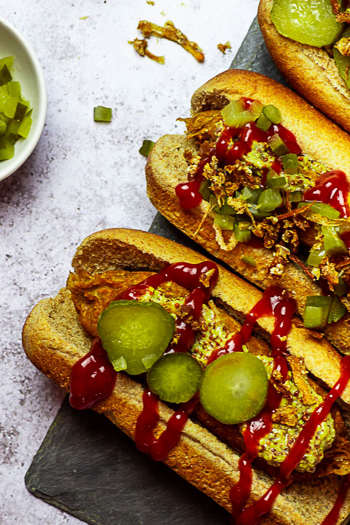 Vegan Hot Dogs made with Seitan (Gluten), Chickpeas, Tahini, Beetroot. Vegetarian Hot Dog with Mustard, Ketchup, Pickles and french fried onions