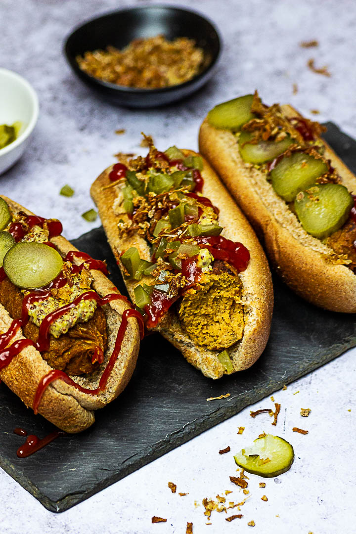 Vegan Hot Dogs made with Seitan (Gluten), Chickpeas, Tahini, Beetroot. Vegetarian Hot Dog with Mustard, Ketchup, Pickles and french fried onions