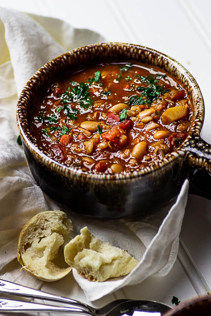 Vegane serbische weiße Bohnensuppe zubereitet aus weißen Bohnen, Grünkern, stückige Tomaten in einer Schüssel serviert