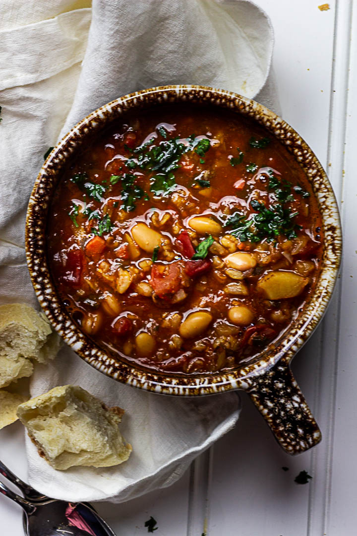 Vegane serbische weiße Bohnensuppe zubereitet aus weißen Bohnen, Grünkern, stückige Tomaten serviert in einer Schüssel