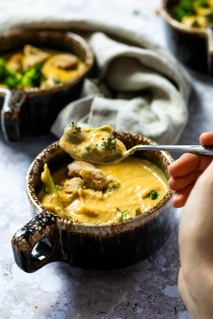 Vegan, wfpb Broccoli Cheddar Soup served in a bowl with homemade croutons and roasted broccoli.