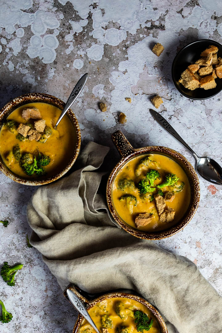 Vegan, wfpb Broccoli Cheddar Soup served in a bowl with homemade croutons and roasted broccoli.