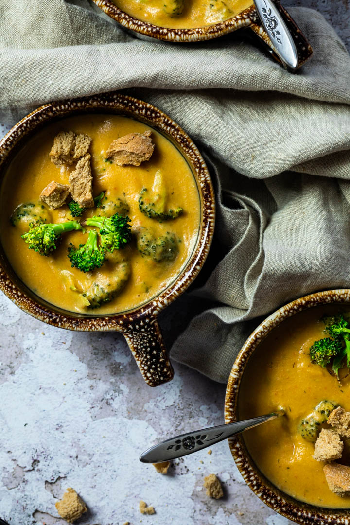 Vegan, wfpb Broccoli Cheddar Soup served in a bowl with homemade croutons and roasted broccoli.