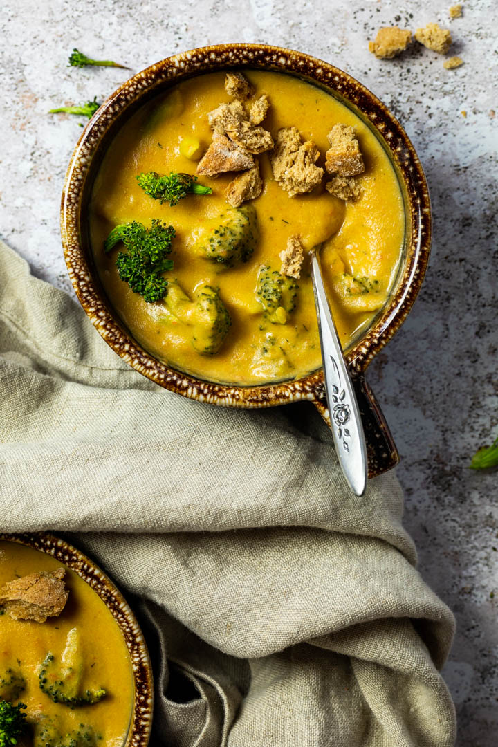 Vegan, wfpb Broccoli Cheddar Soup served in a bowl with homemade croutons and roasted broccoli.