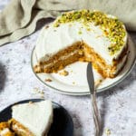 Ganzer Karottenkuchen auf einem Teller mit zwei fehlenden Stücken. Du siehst die Schichten des Karottenkuchens