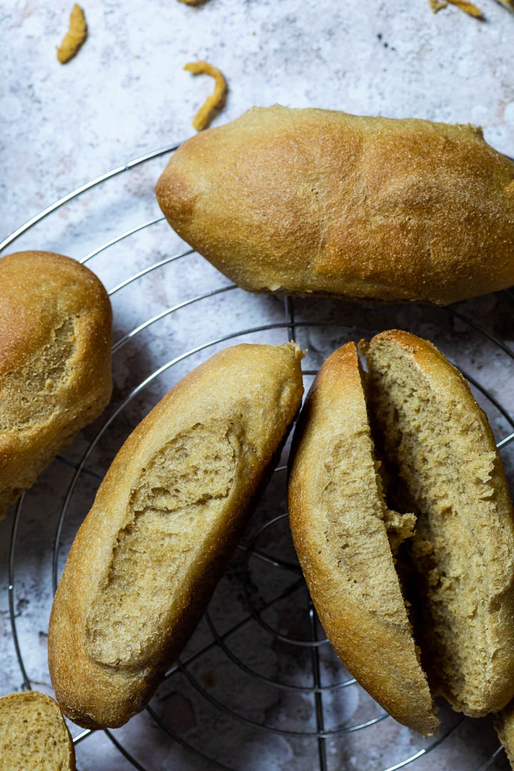 Selbstgemachte vegane Vollkornweizen-Hot Dog Brötchen auf einem Gitter.