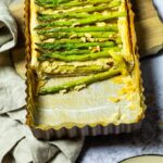 A cutted vegan asparagus tart laying on a wooden board.