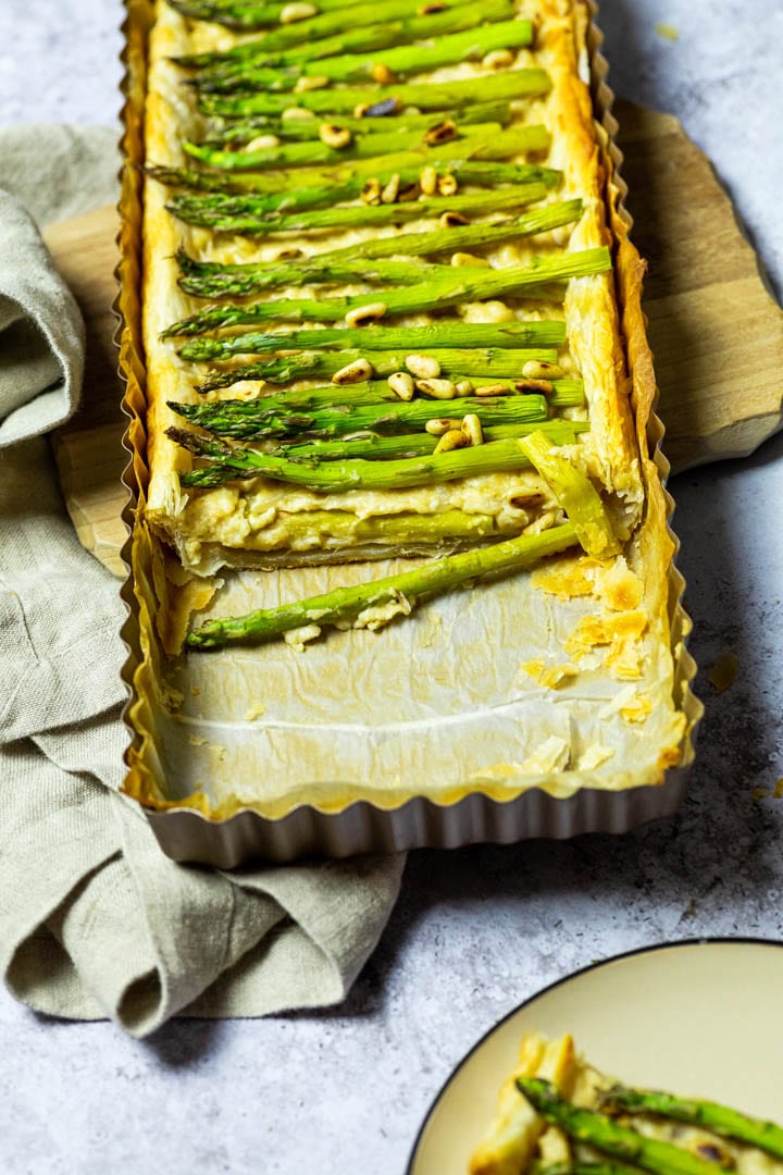 A cutted vegan asparagus tart laying on a wooden board.