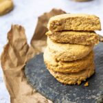 A stack of vegan buttermilk biscuits. Wfpb biscuits in the back blurred. And on top of the stack two half biscuits where you see the inside