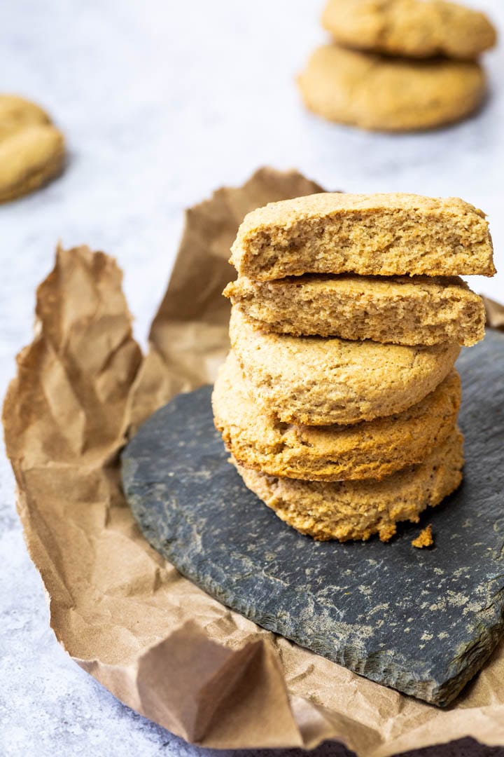 A stack of vegan buttermilk biscuits. Wfpb biscuits in the back blurred. And on top of the stack two half biscuits where you see the inside