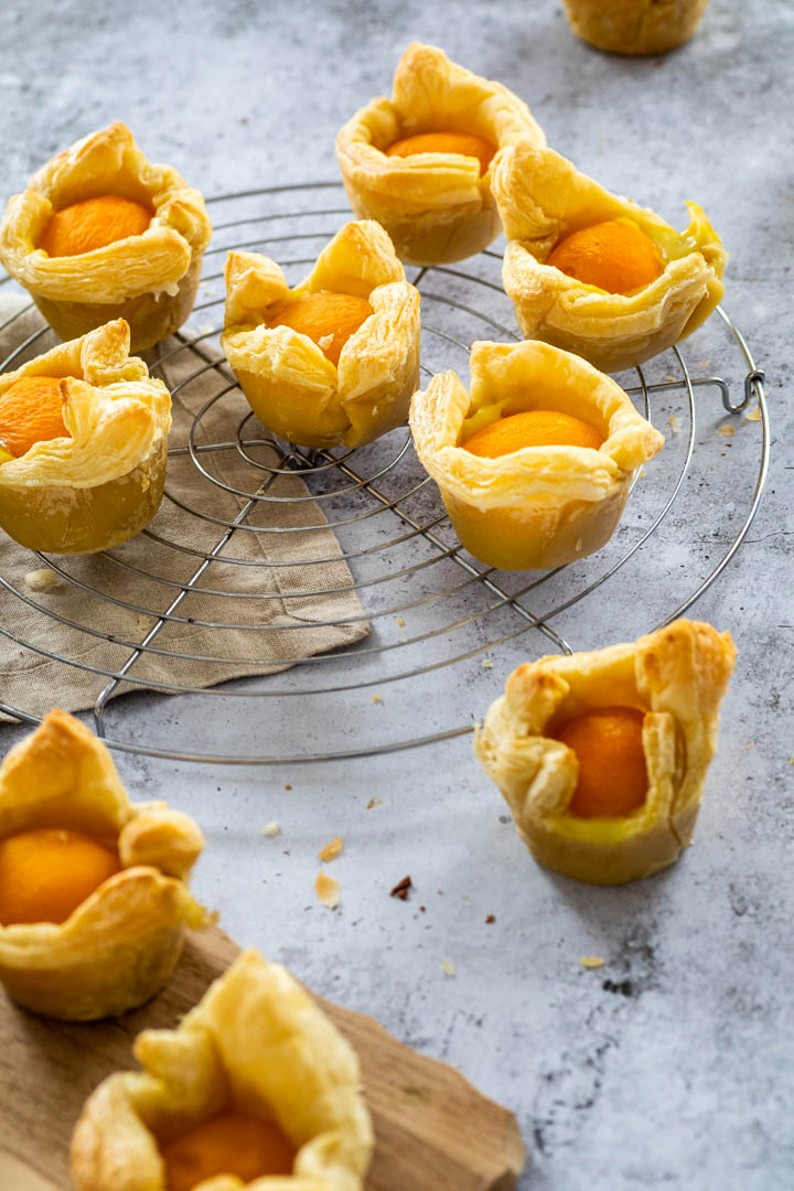 Vegan Custart Apricot Cups on a wire rack with blurred apricot cups in the front on a wooden board