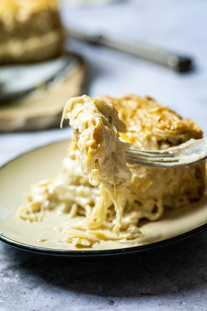 Veganer Zwiebelkuchen auf einem Teller mit einem Stück auf einer Gabel