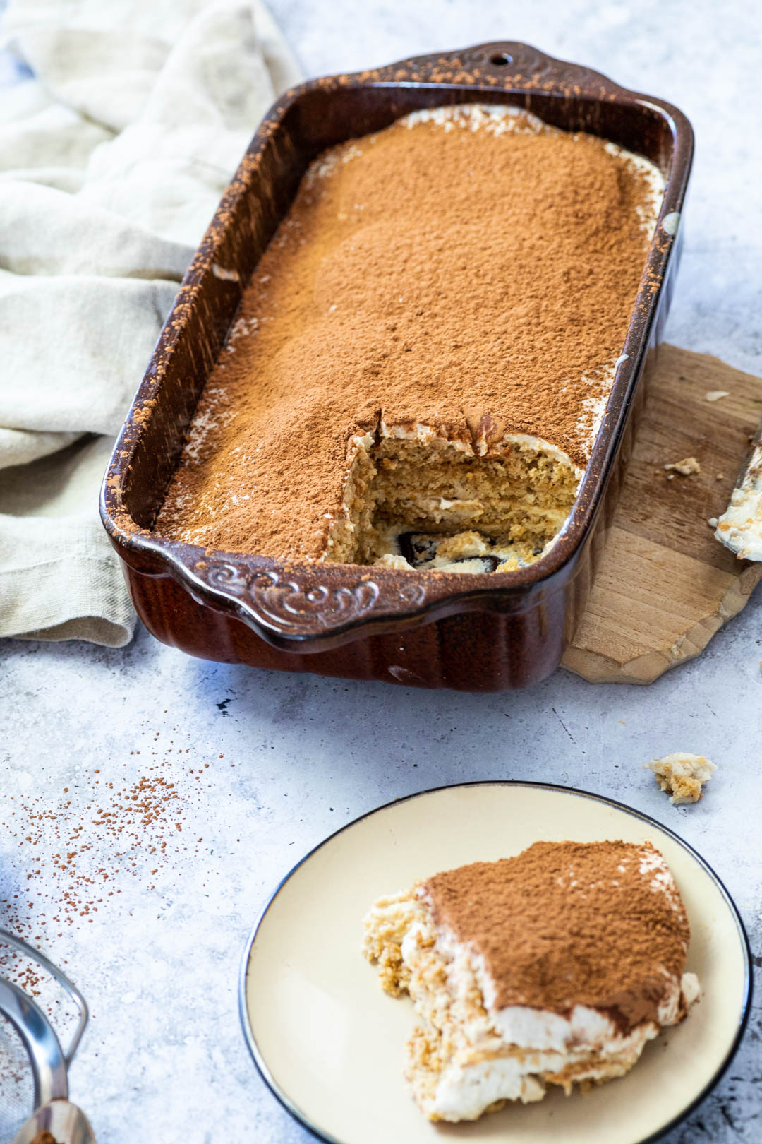 Tiramisu in a pan an a piece of vegan tiramisu on a plate