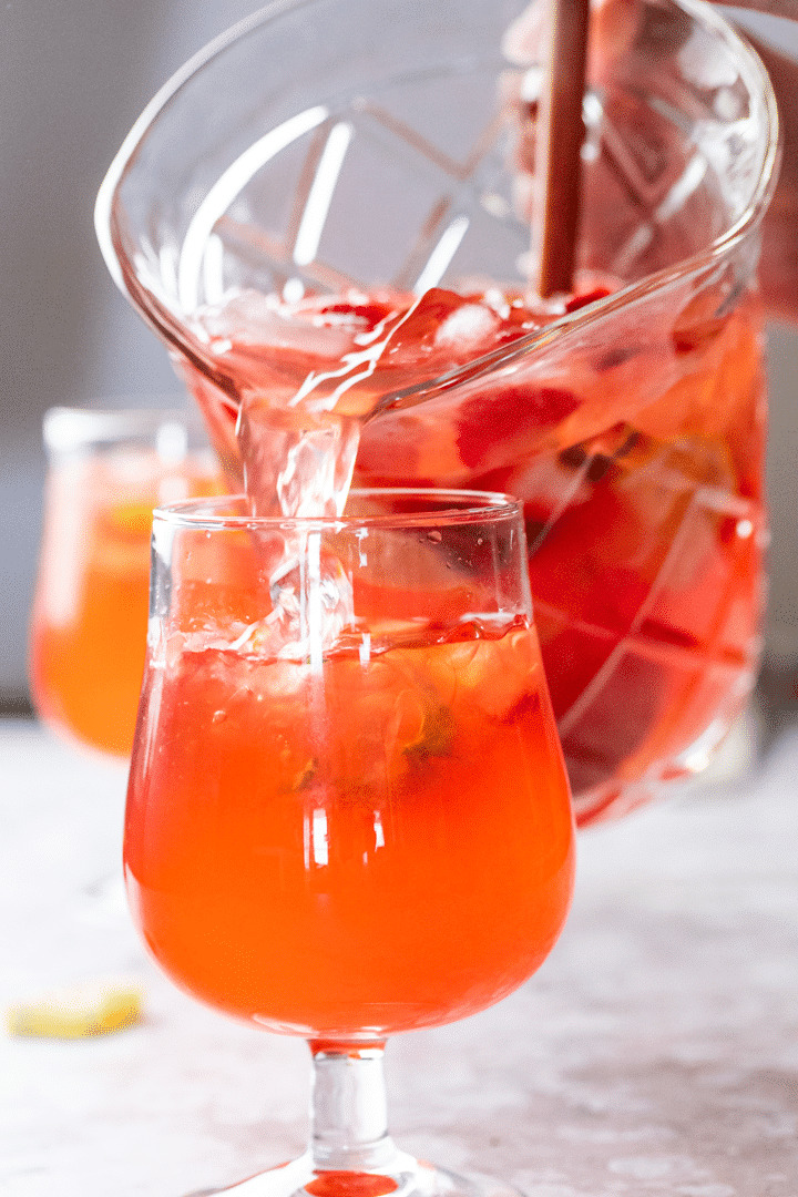 Glass with strawberry basil lemonade and a pitcher with lemonade