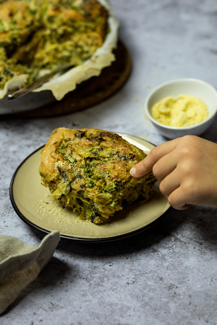 One Artichoke Spinach Pinwheel on a plate with a hand