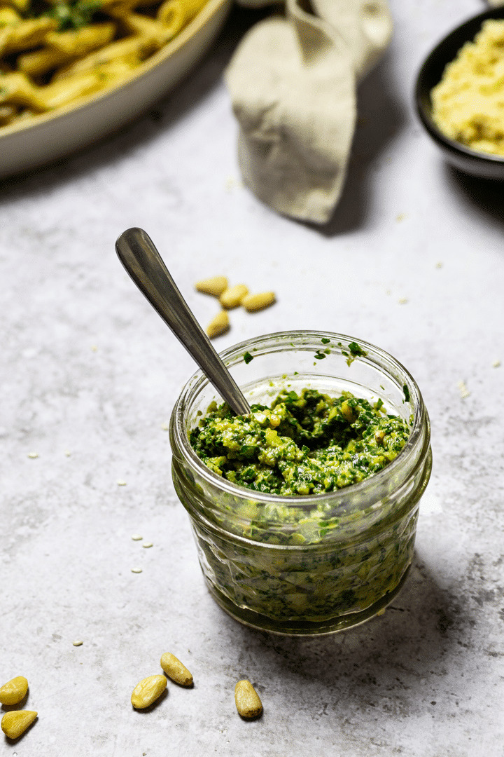 Homemade vegan basil pesto without oil in a jar with a spoon in the jar. 