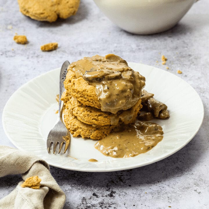 Stack of vegan biscuits on a plate with a wfpb gravy
