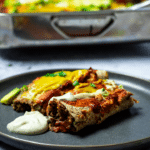 Zwei Enchiladas auf einem Teller mit dem Auflauf im Hintergrund