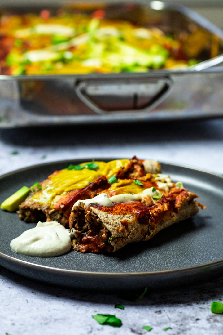 Zwei Enchiladas auf einem Teller mit dem Auflauf im Hintergrund