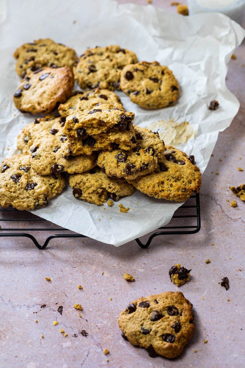 Vegan chocolate chip cookies with pieces of chocolate on a grid with baking paper