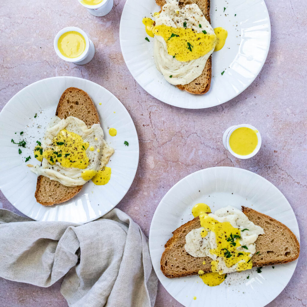 3 plates with vegan fried eggs and some egg holder with vegan egg yolk