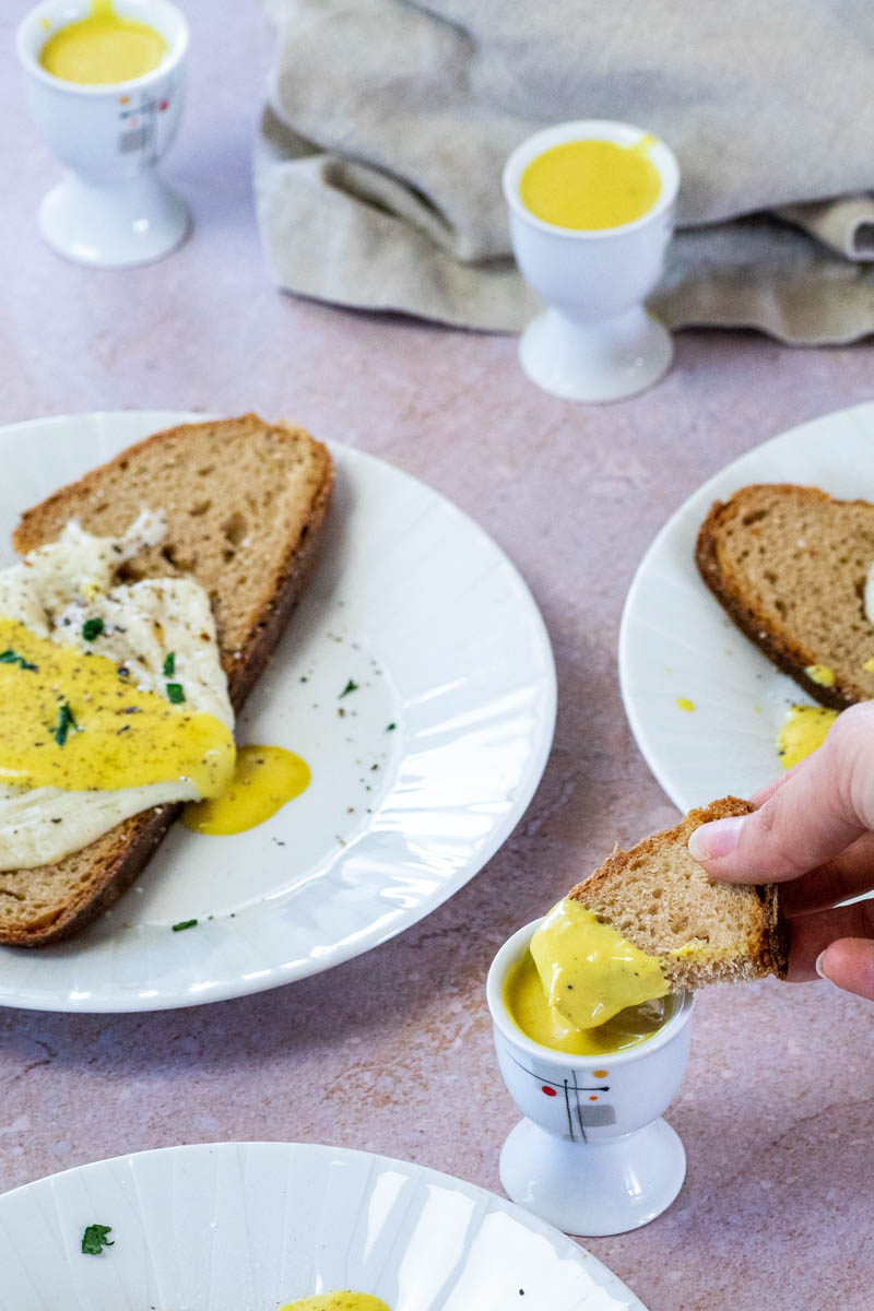 Ein Brot in veganes Eigelb tauchen