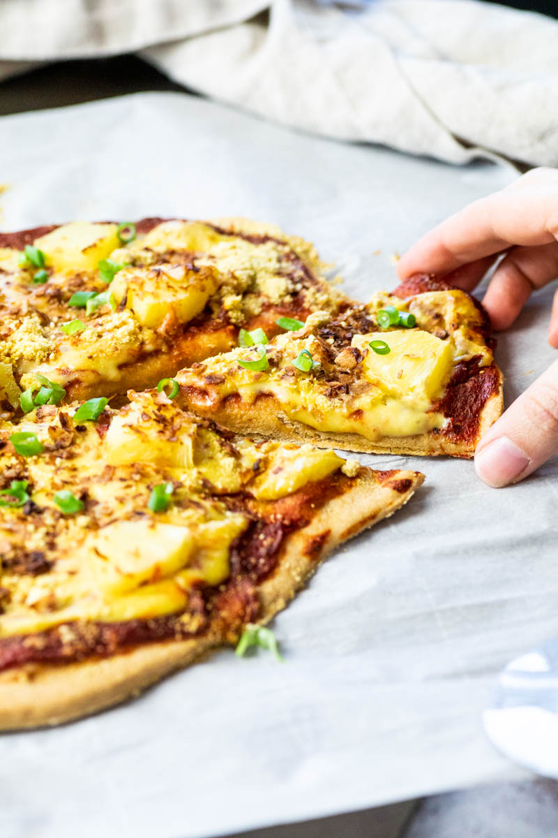 Ein veganes Pizza Hawaii-Stück schnappen