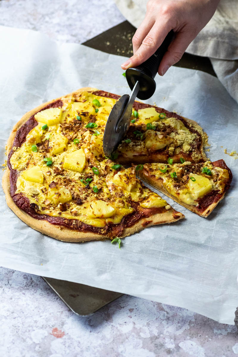 Thin crusted pizza hawaii which gets cut with a pizza cutter