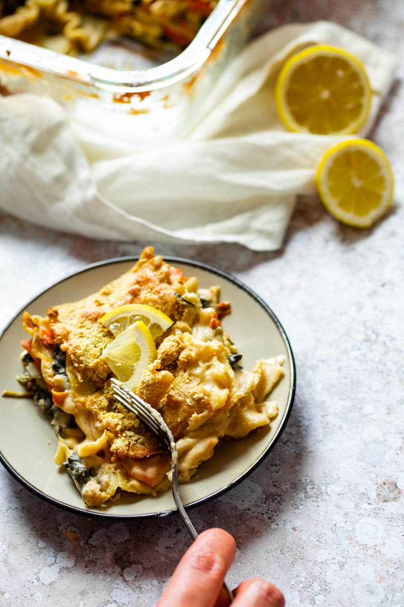 Weiße Lasagne auf einem Teller mit der Gabel das Lasagne-Stück schneiden