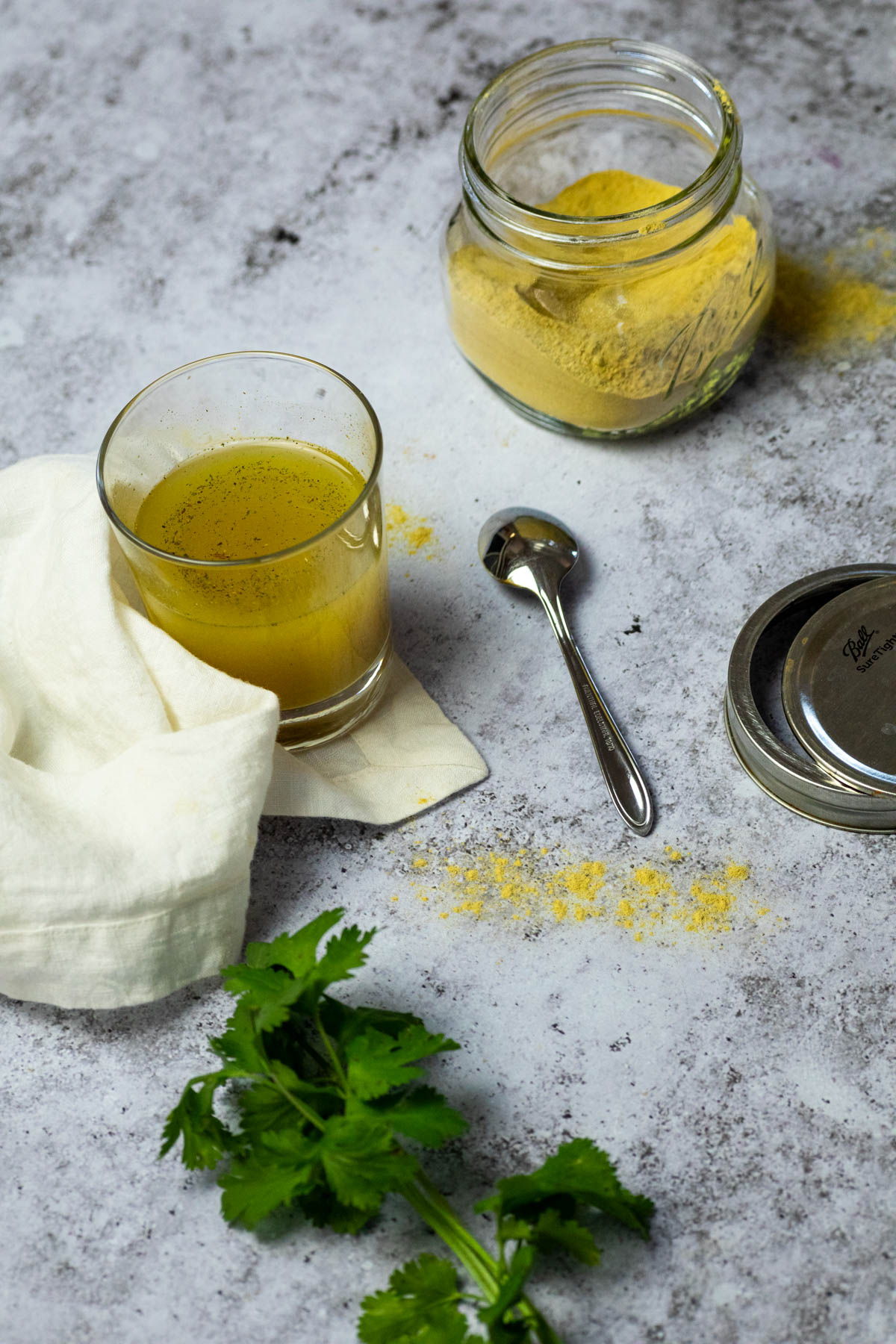 A glass with chicken bouillon broth and a jar with the homemade chicken broth powder