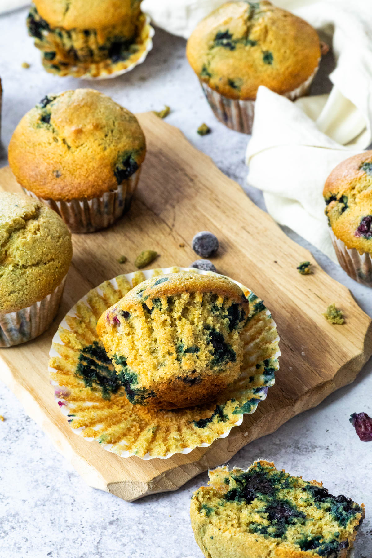 Blaubeermuffins, die auf einem Holzbrett und herum liegen.