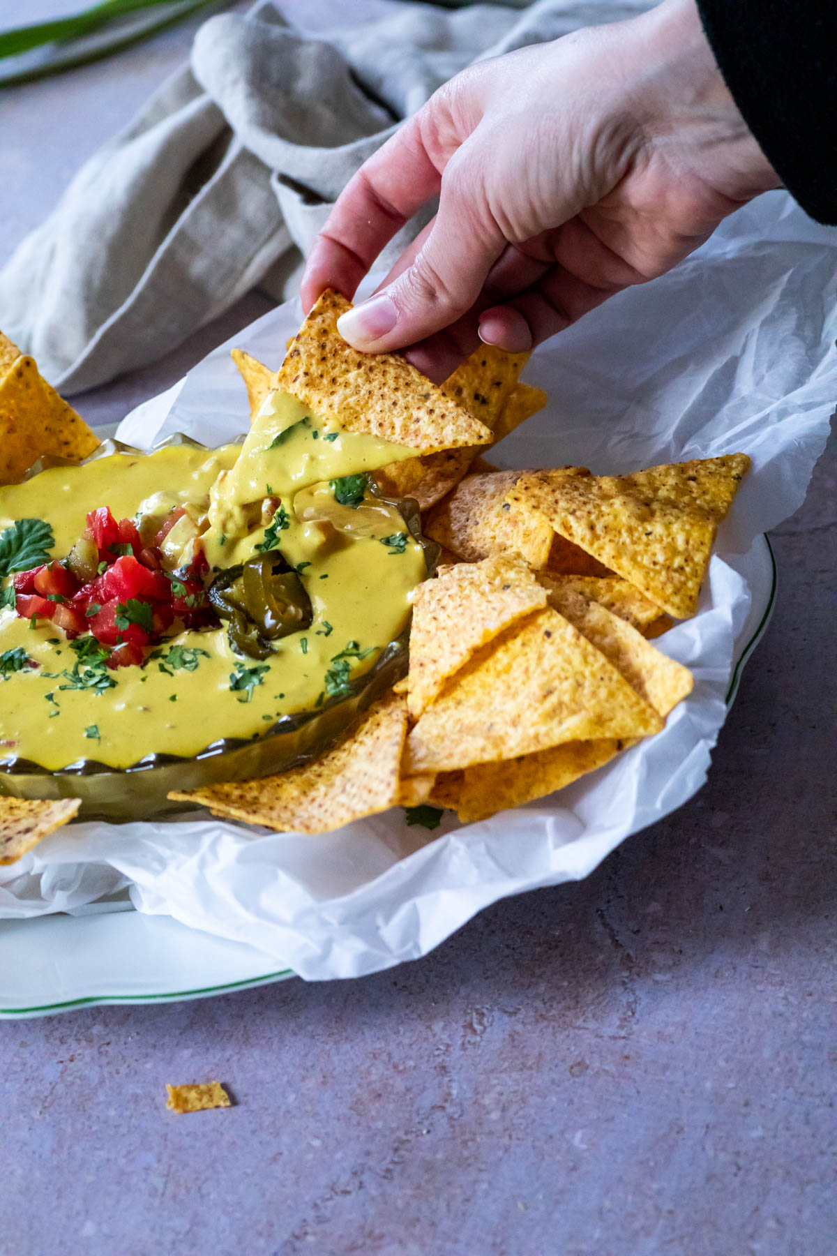 einen Chip halten und in den veganen Queso-Dip tauchen