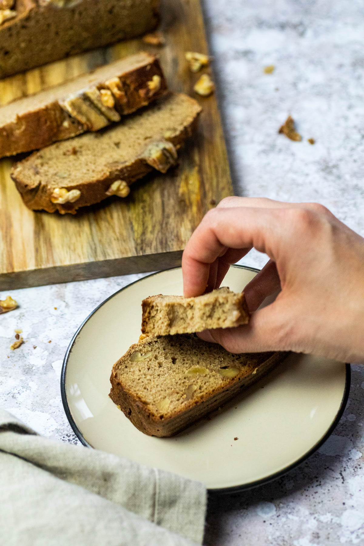 Eine Scheibe veganes Bananenbrot auf einem Teller mit einem Stück Brot.