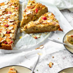 Veganer Rhabarberkuchen mit einem in Scheiben geschnittenen Stück im Fokus