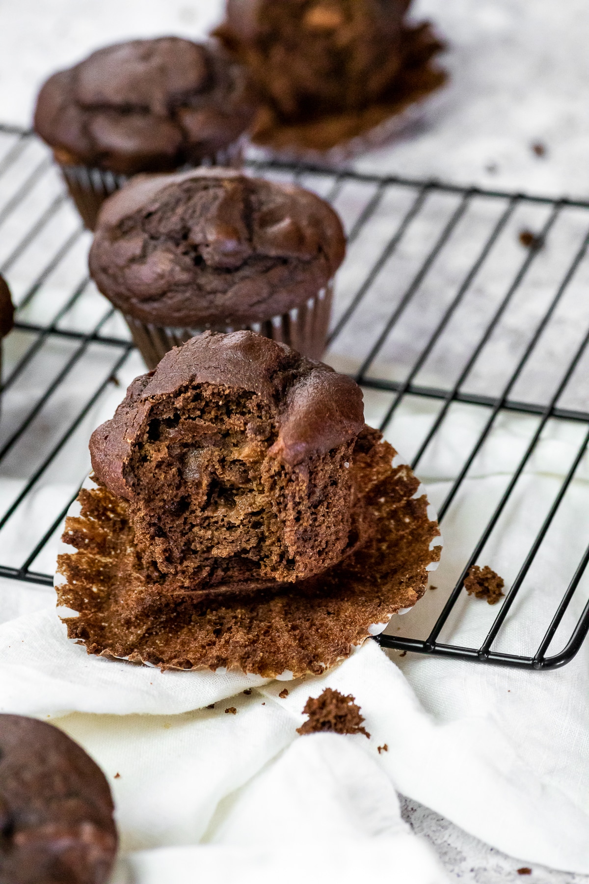 Chocolate Muffin with one bite missing and sitting on the muffin paper.