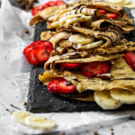 Gerade Ansticht auf die gefüllten Crepes mit Schokoladenhummus, Banane und Erdbeeren