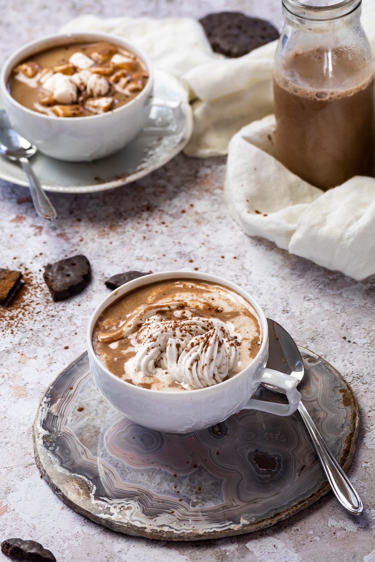 2 cups of hot chocolate one with coconut cream and one with marshmallows topped.