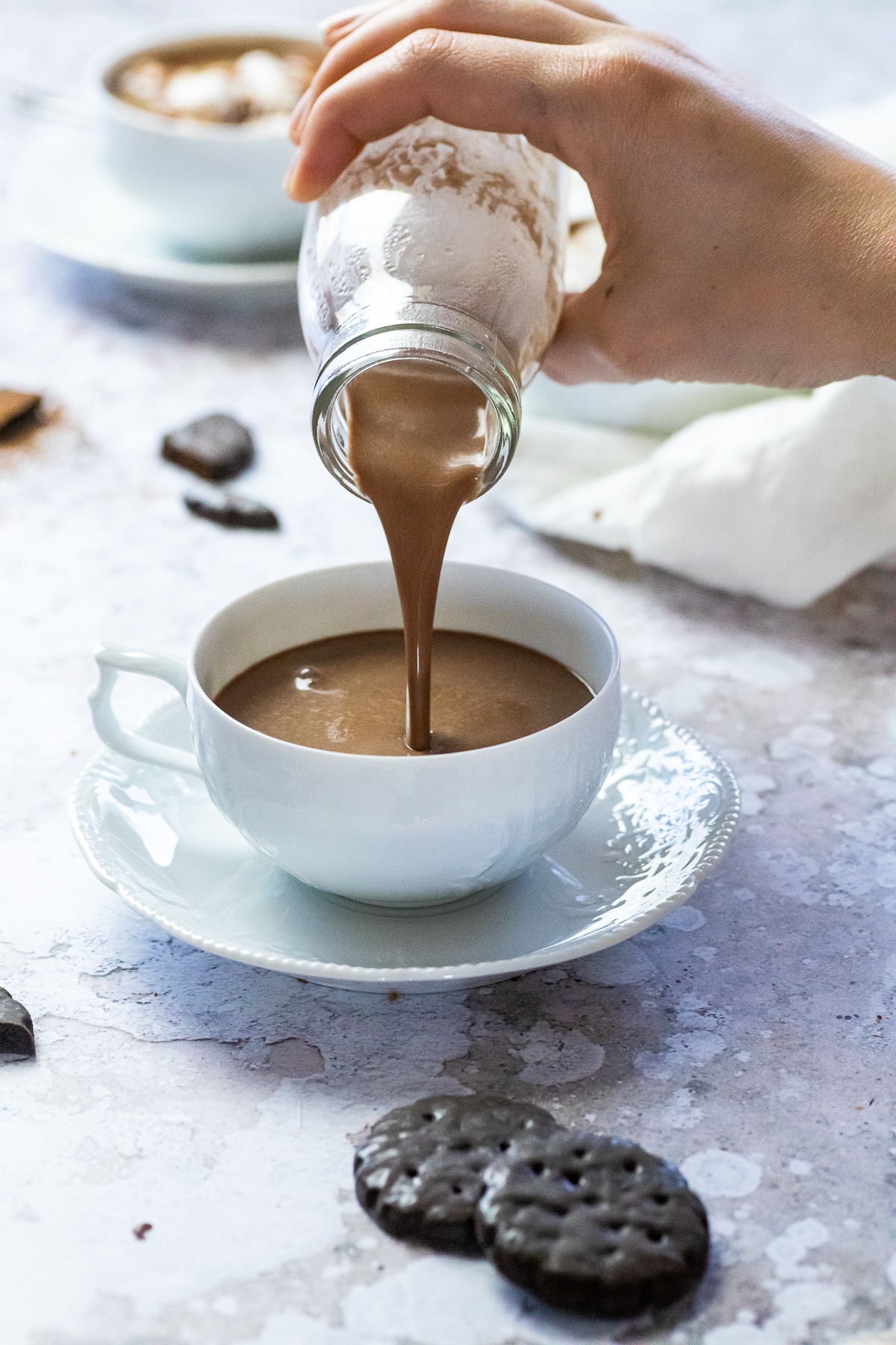 Vegane heiße Schokolade in einer Tasse mit etwas mehr in die Tasse gießen.