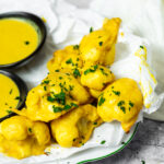 Bird View on a serving plate with honey mustard cauliflower wings and with two dipping bowls.